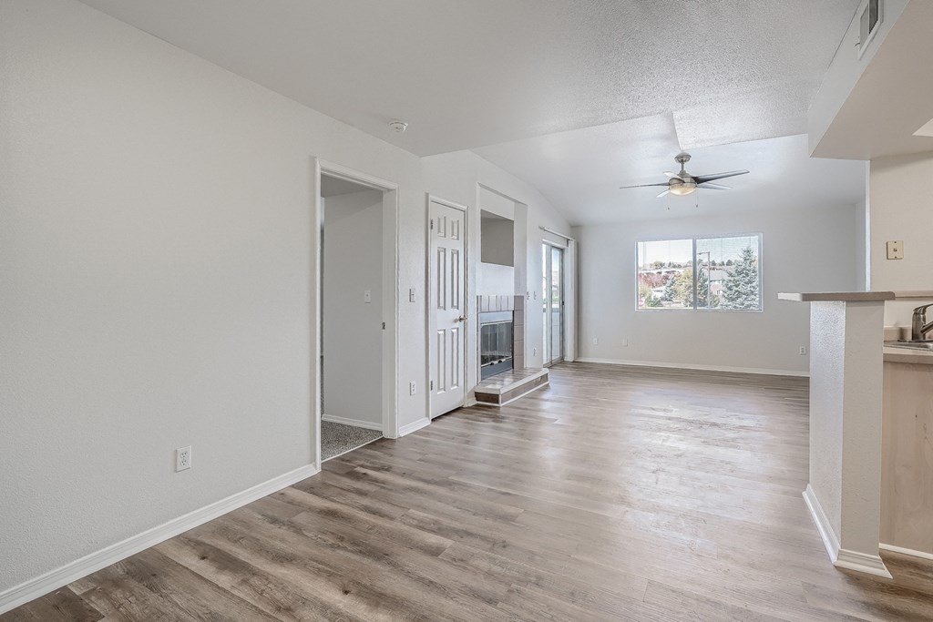 an empty living room and kitchen with a ceiling fan