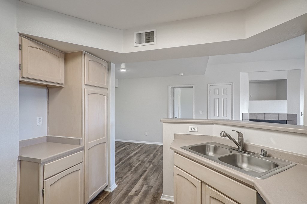 an empty kitchen with wood flooring and a stainless steel sink