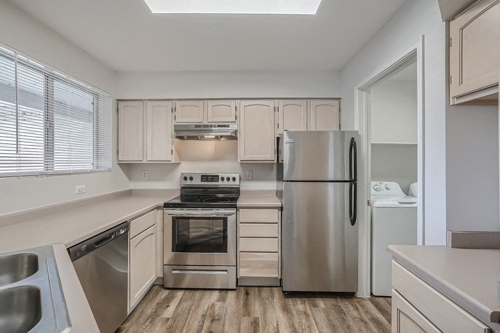an empty kitchen with stainless steel appliances and white cabinets
