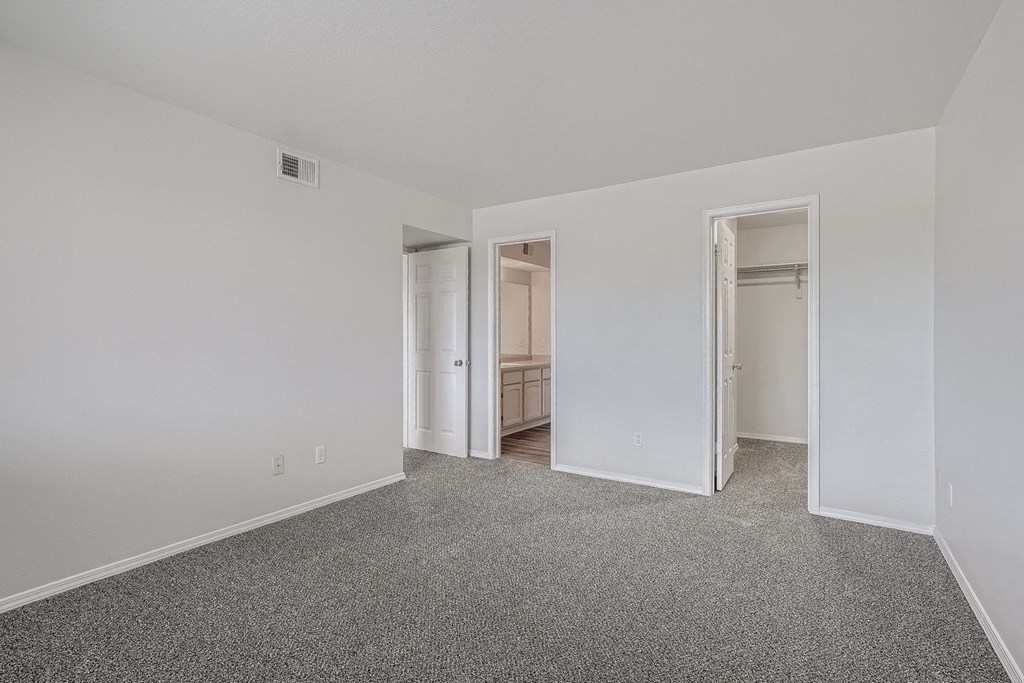 an empty bedroom with white walls and carpeting