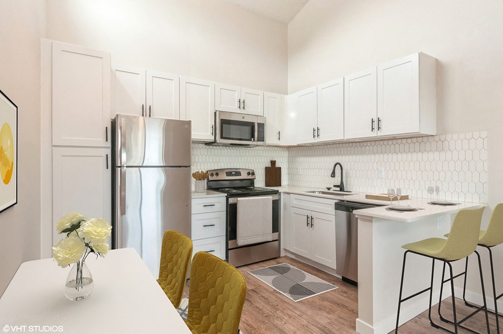a kitchen with white cabinets and stainless steel appliances and a table with chairs