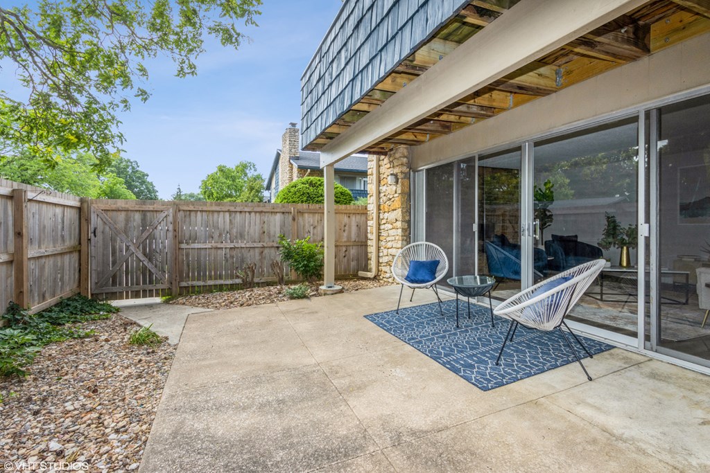 a patio with two chairs and a table in front of a house