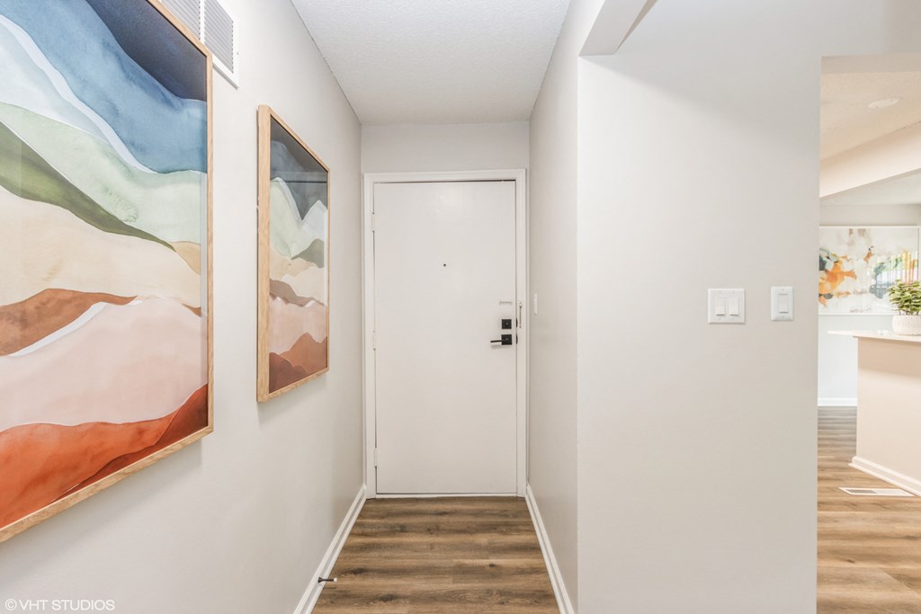 a hallway with a white door and paintings on the wall