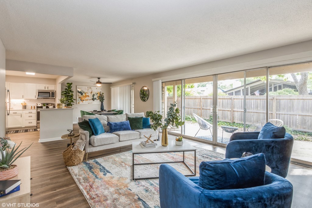 the living room and kitchen of a house with blue chairs and couches