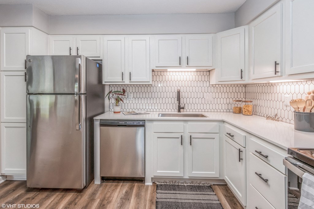 a white kitchen with stainless steel appliances and white cabinets