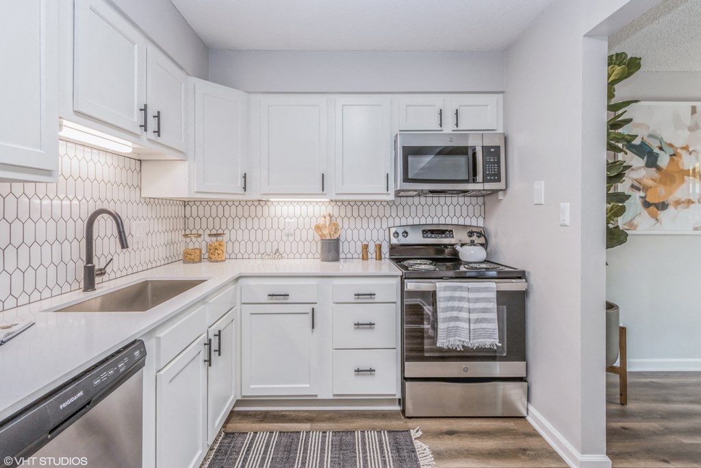 a white kitchen with white cabinets and stainless steel appliances and a microwave