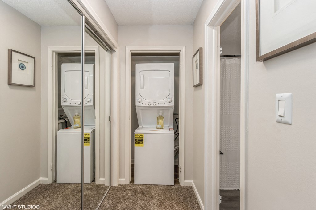 a laundry room with a washer and dryer and a mirror on the wall