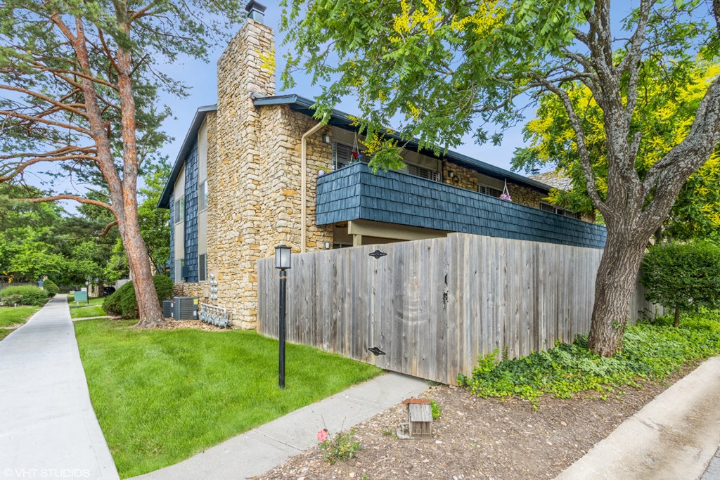 a home with a wooden fence and a stone house behind it