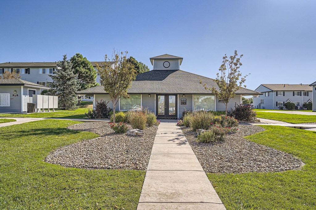 a pathway leading to a building with a clock on the roof