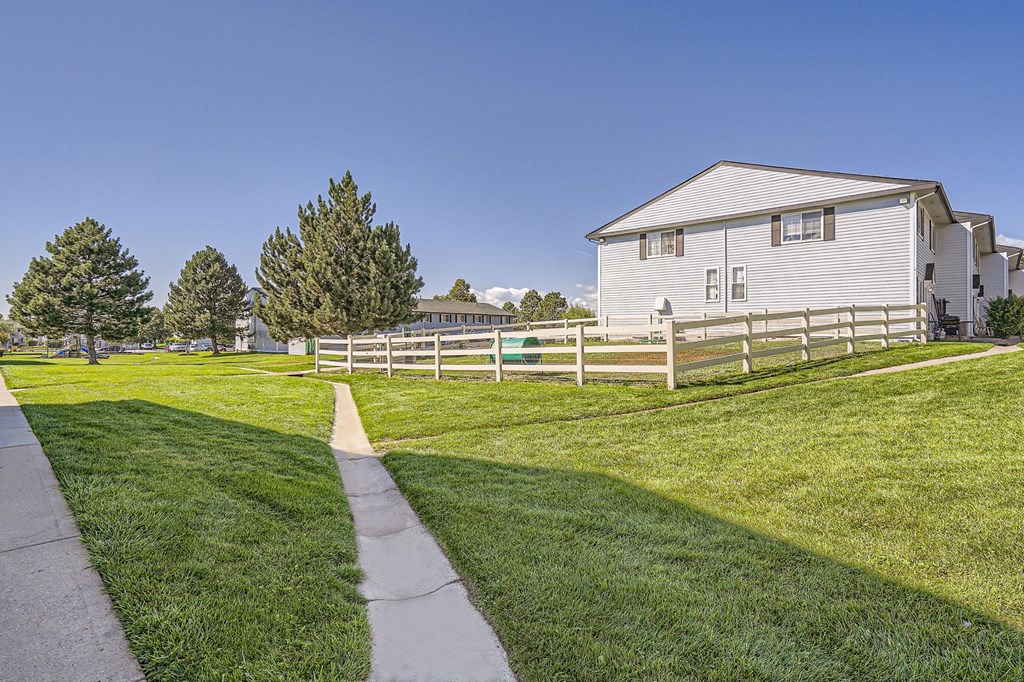 a white house with a white fence and a green lawn