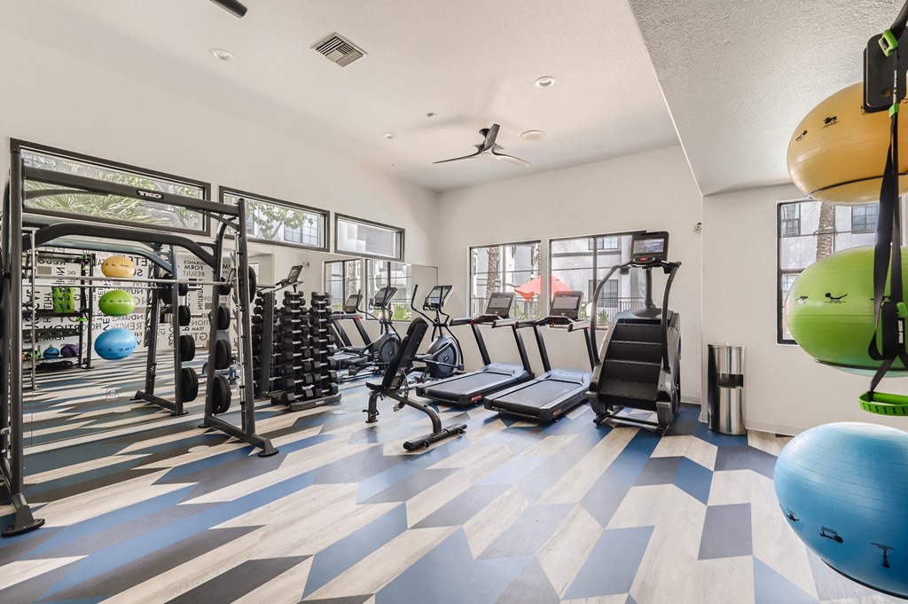 a gym with cardio machines and weights on a checkered floor