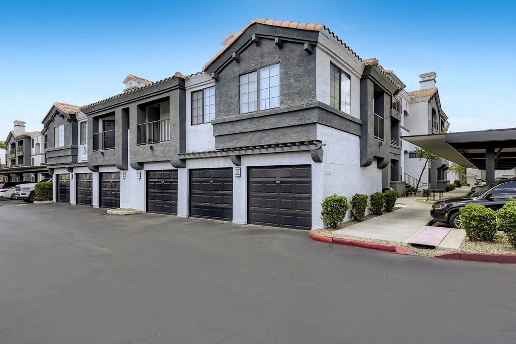 a large grey and white building with black garage doors