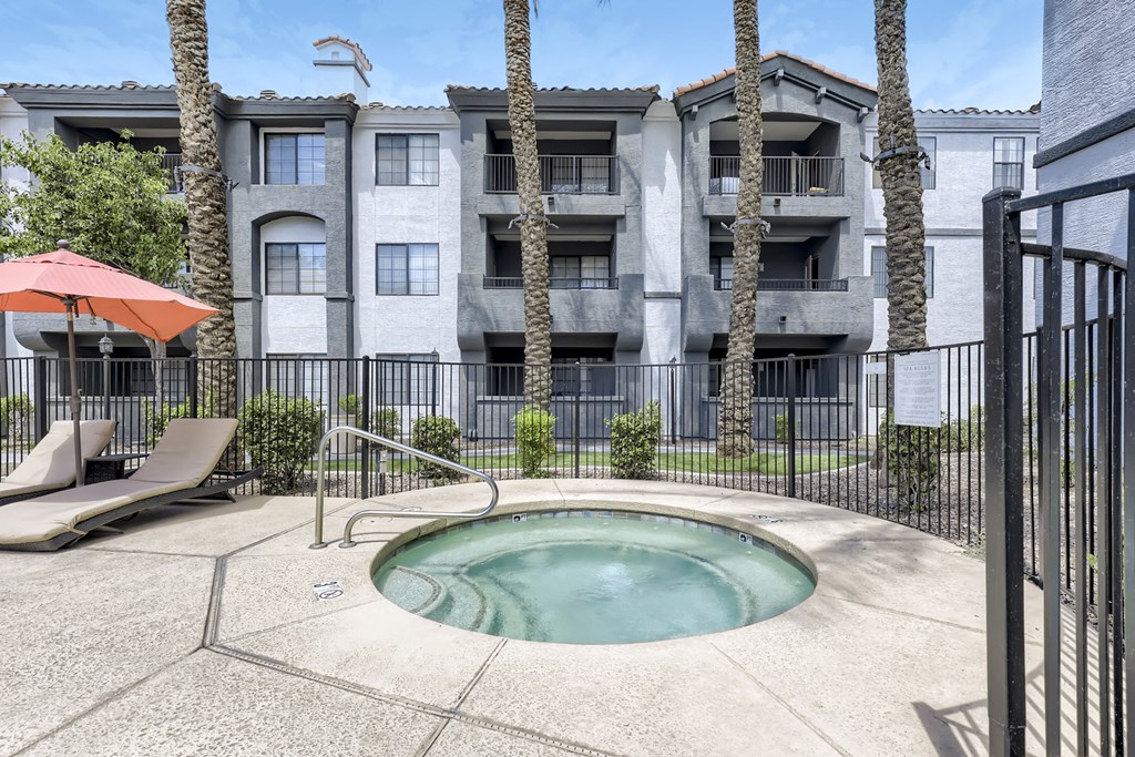 a small pool is in front of an apartment building with palm trees