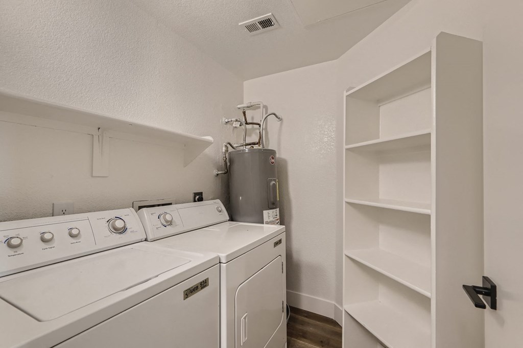 a white laundry room with a washer and dryer and white shelves