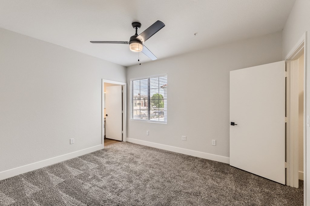an empty living room with carpet and a ceiling fan