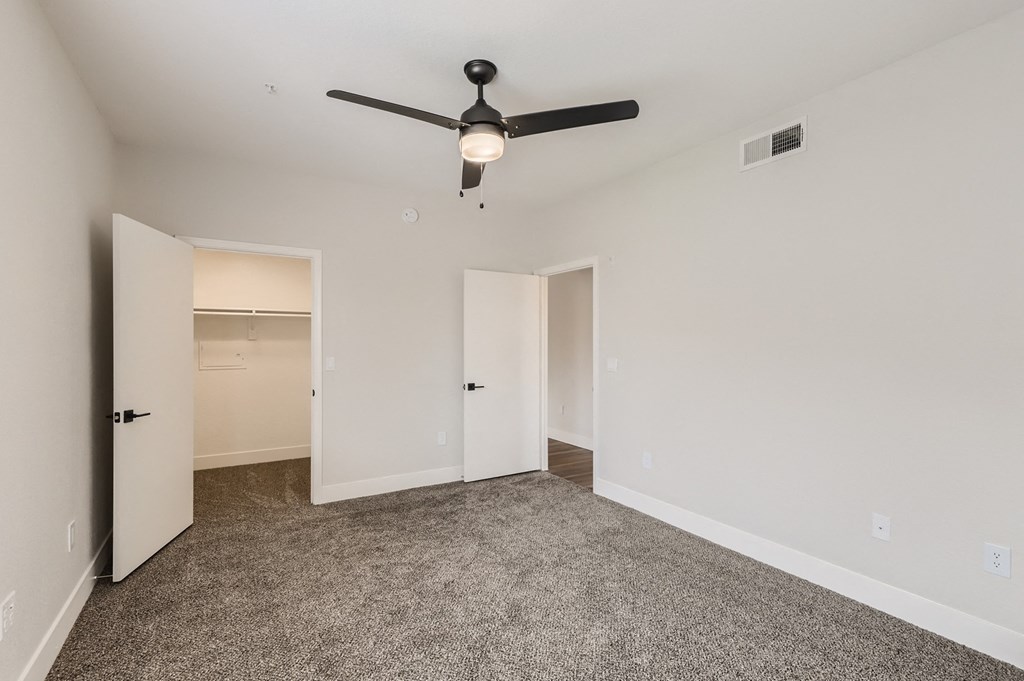 an empty bedroom with a ceiling fan and a closet