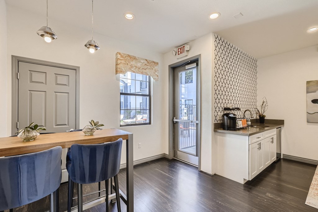 a kitchen and dining area with a table and chairs and a door to a balcony
