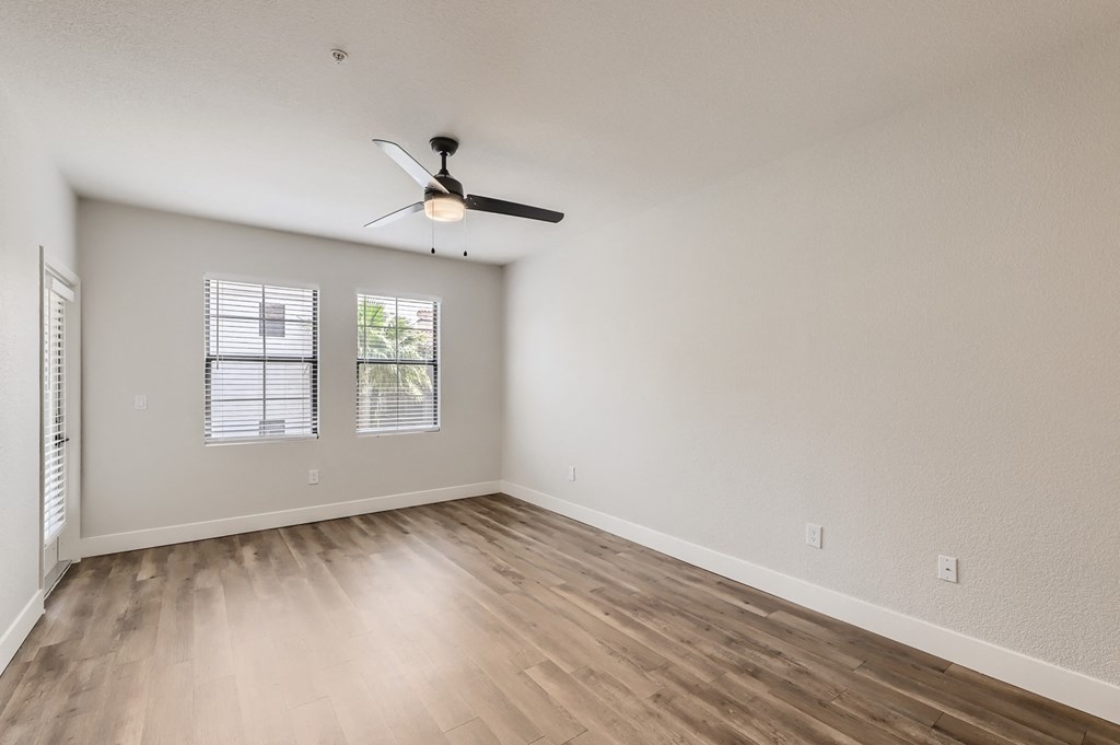 the spacious living room with hardwood floors and a ceiling fan