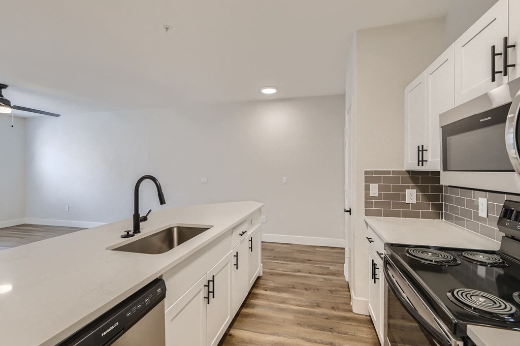 a kitchen with white cabinets and a sink and a stove