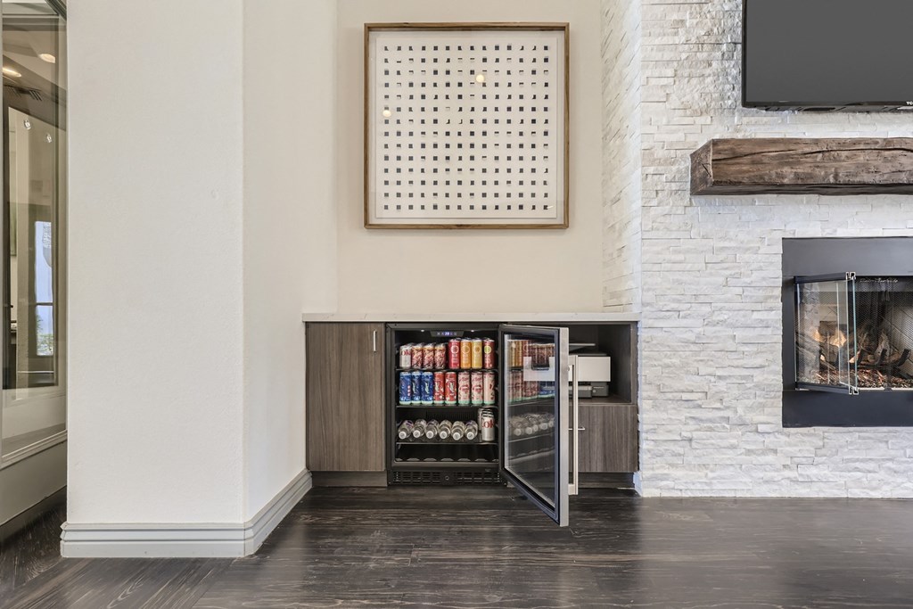a living room with a fireplace and a cabinet with a refrigerator