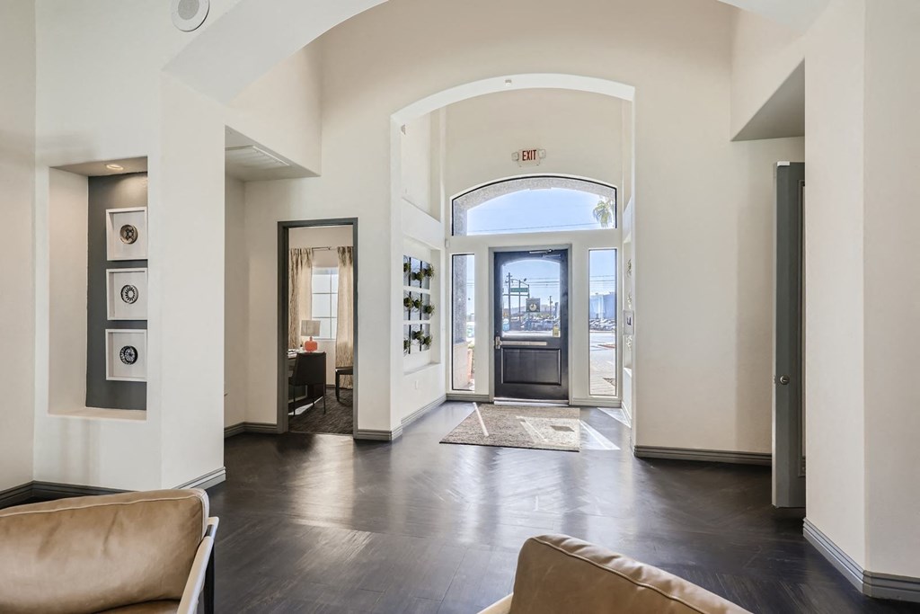a living room with white walls and a wooden floor and a door