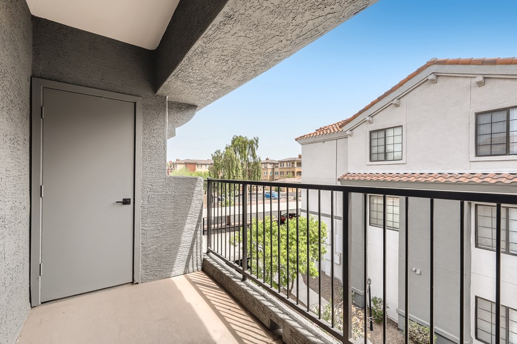 a balcony with a door and a view of a building and some trees