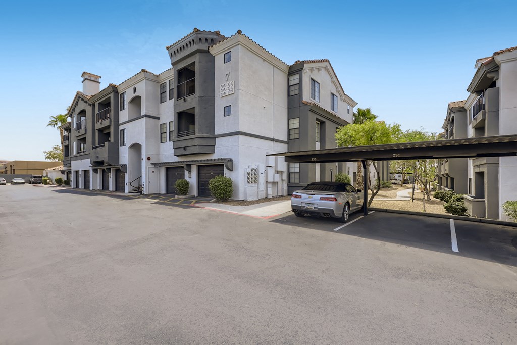 a car is parked under an overpass in front of an apartment building