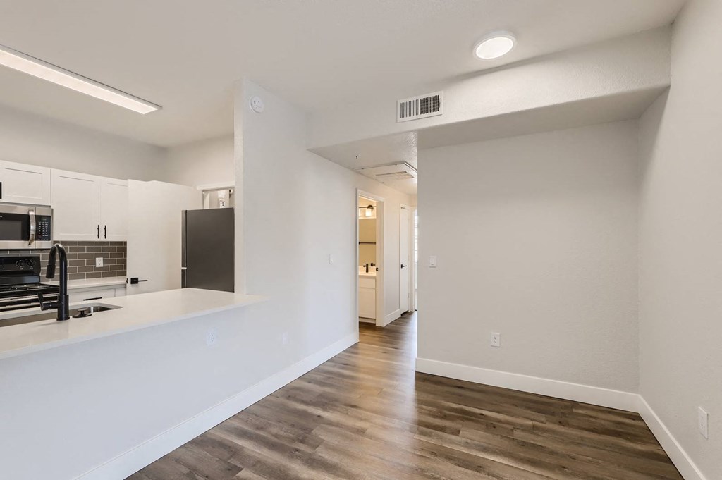 an empty kitchen and living room with white walls and wood floors