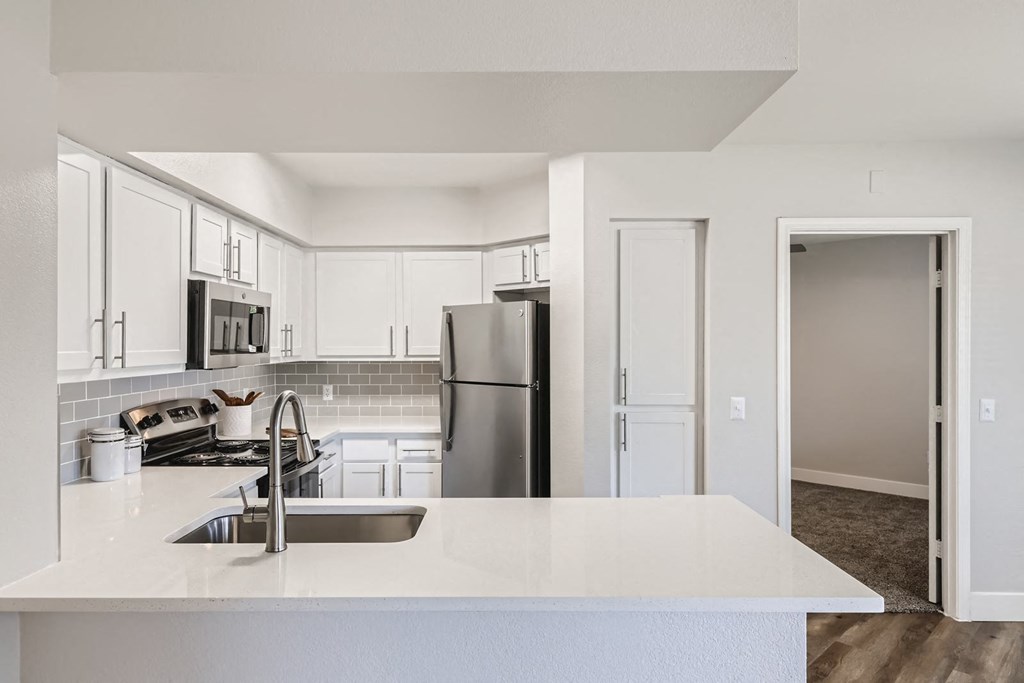 a kitchen with white countertops and stainless steel appliances