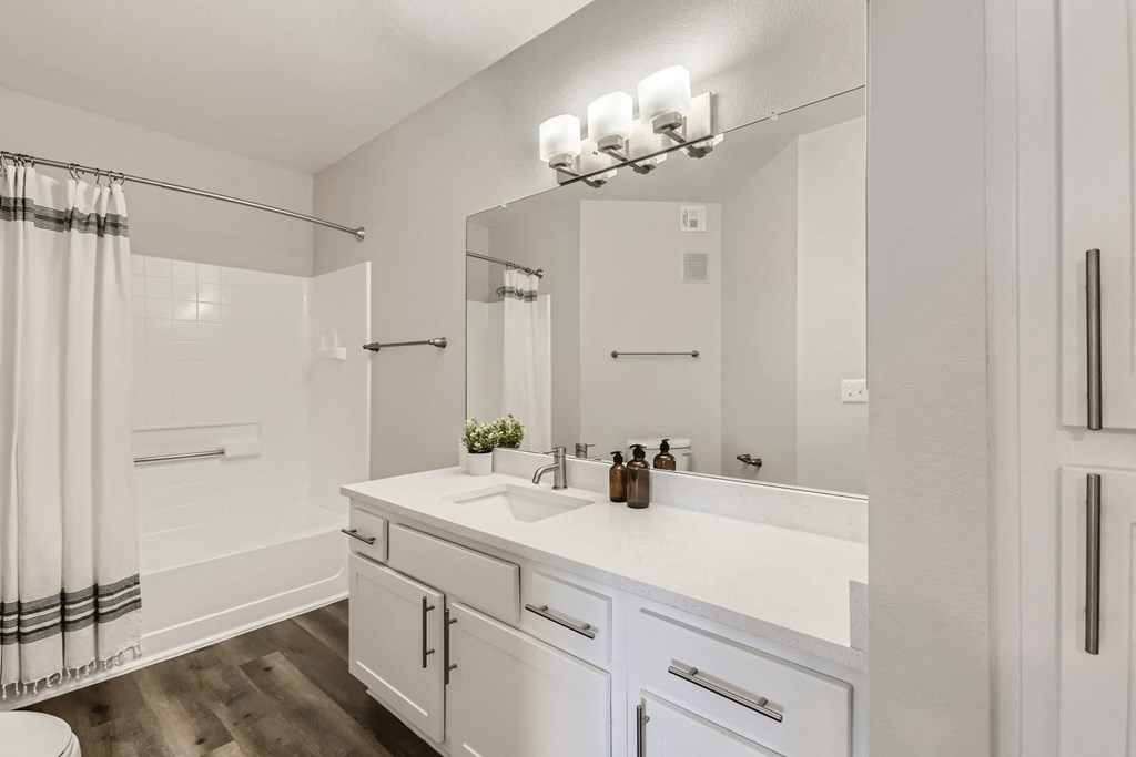 a bathroom with white cabinetry and a white shower curtain