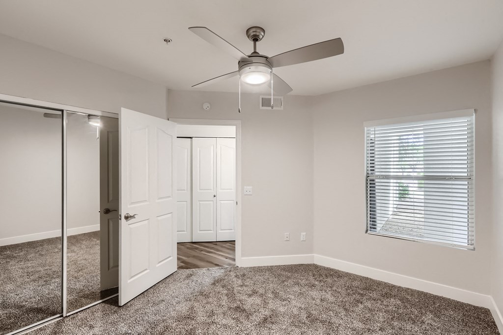 a bedroom with a ceiling fan and mirror