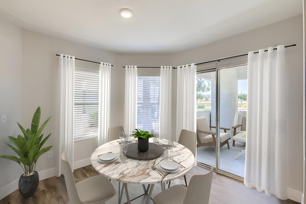a dining area with a round table and chairs and a sliding glass door leading to a patio