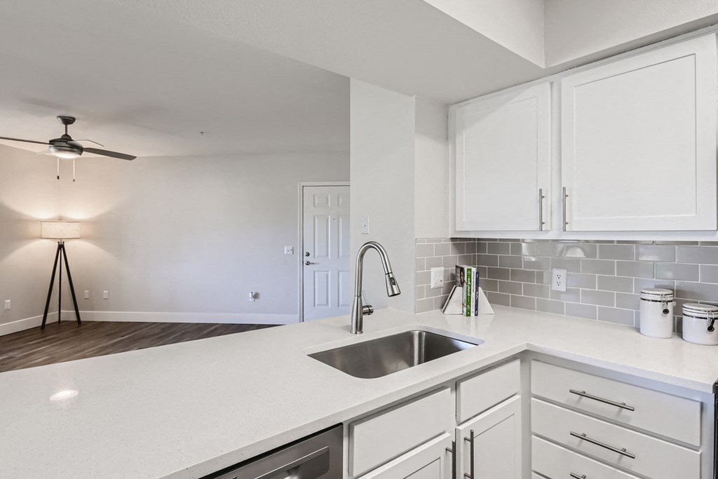 a kitchen with white cabinets and a stainless steel sink