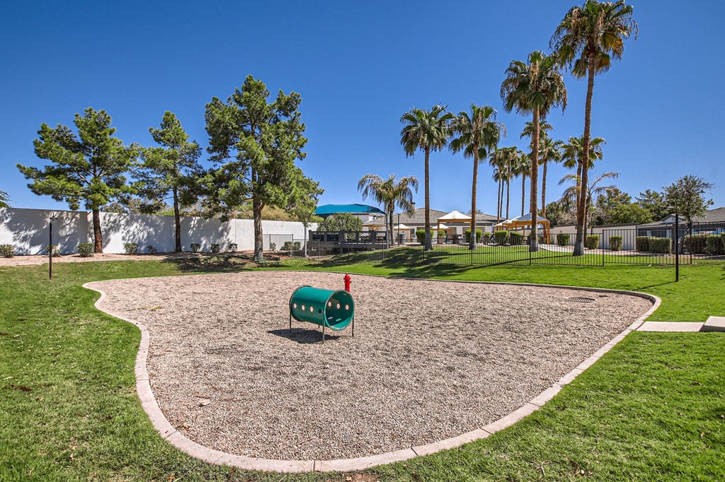 a dog park with a gravel path and trees in the background