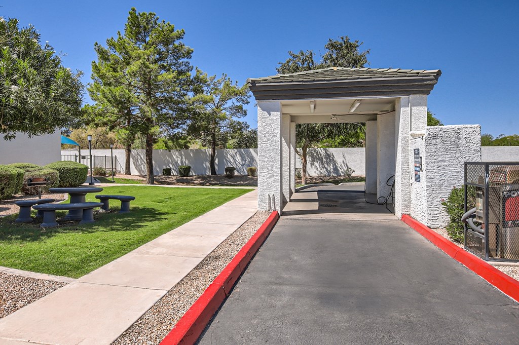 a covered walkway with a picnic table and bench in front of a building