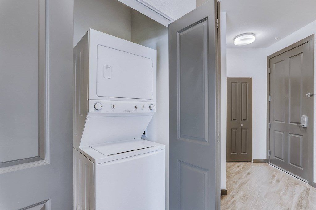 a white washer and dryer in a room with a door to a closet