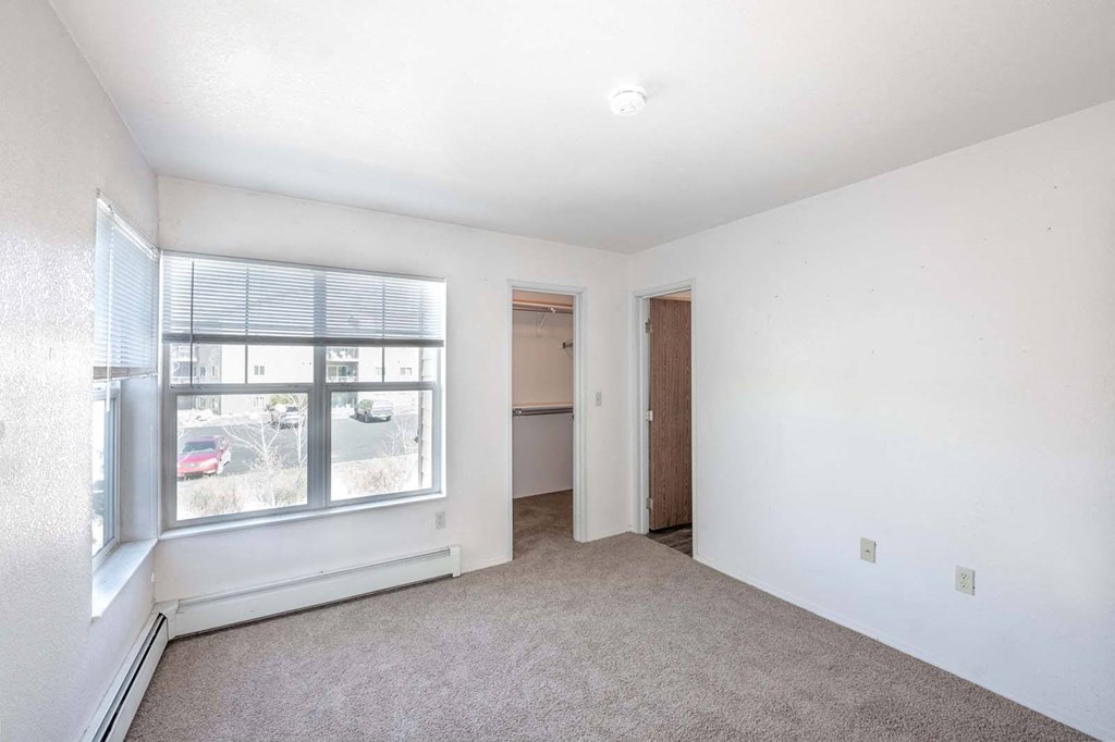 an empty living room with a large window and carpet
