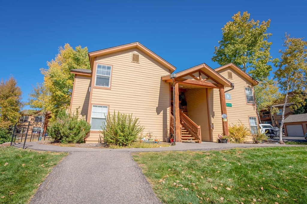 the front of a yellow house with a driveway and a porch