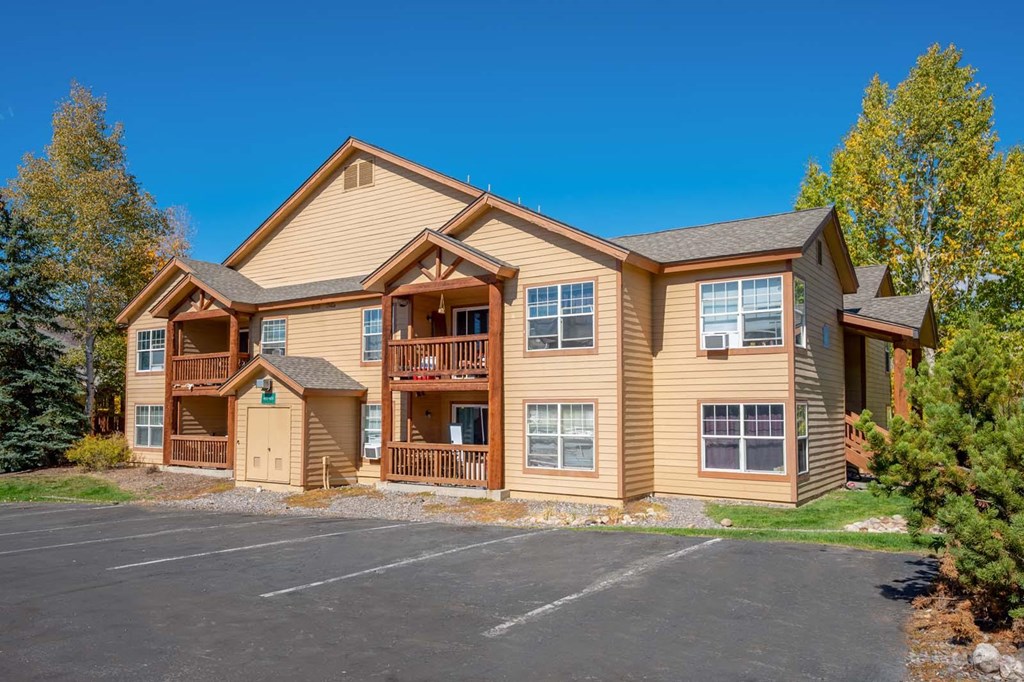 the front of a yellow house with a parking lot