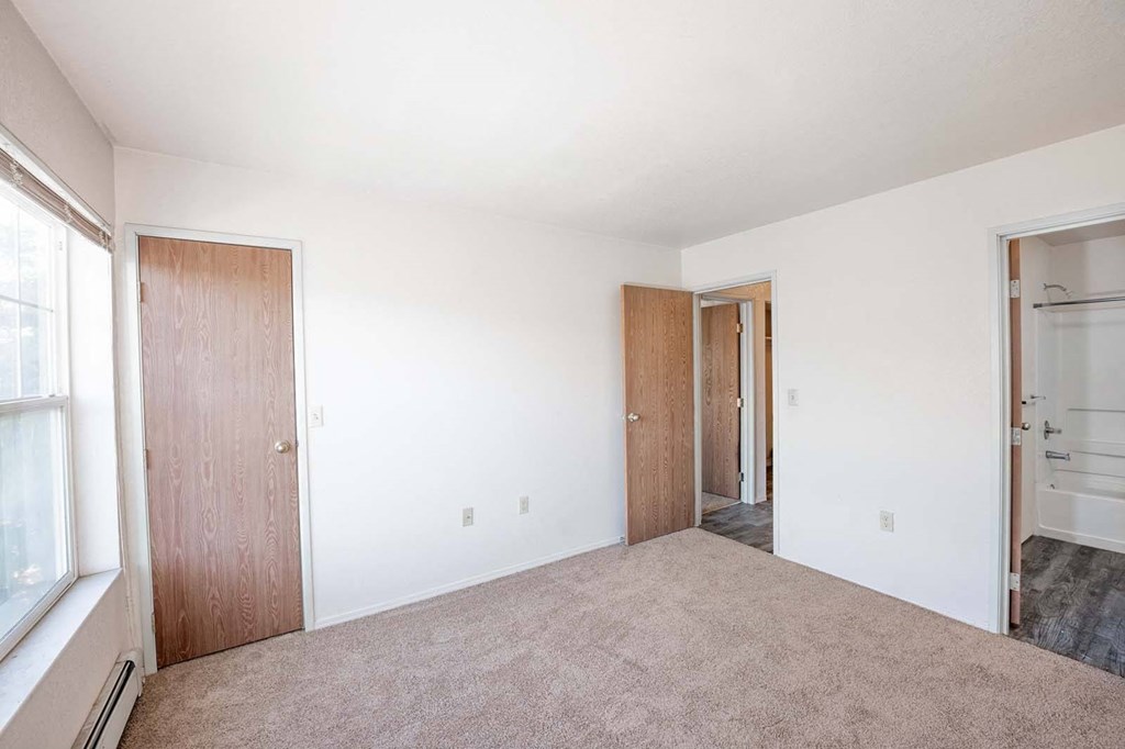 an empty bedroom with white walls and a door to a closet