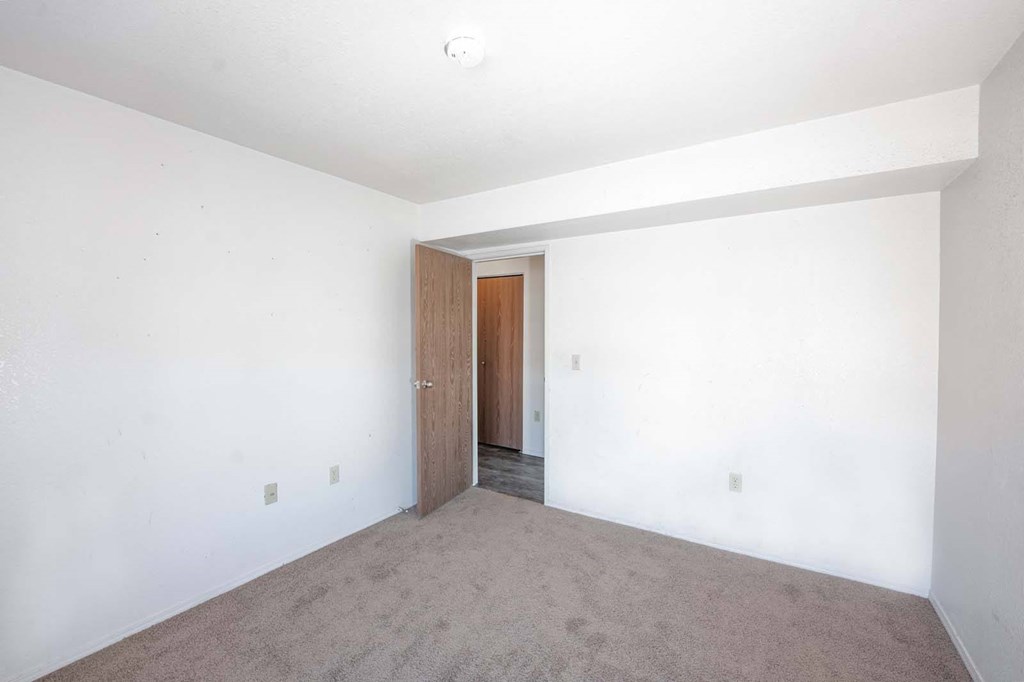 an empty living room with white walls and a wooden door