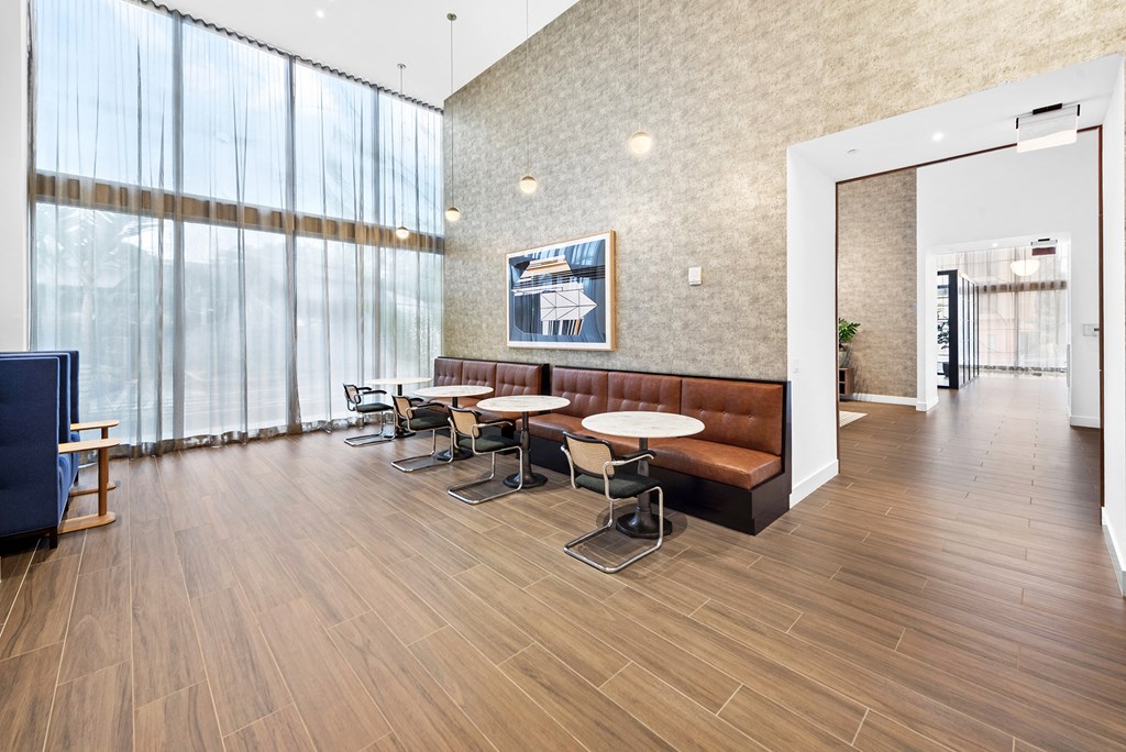 a seating area with tables and chairs in front of a wall of windows