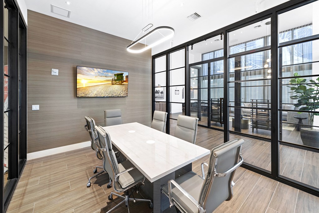 a meeting room with a table and chairs and a tv on the wall