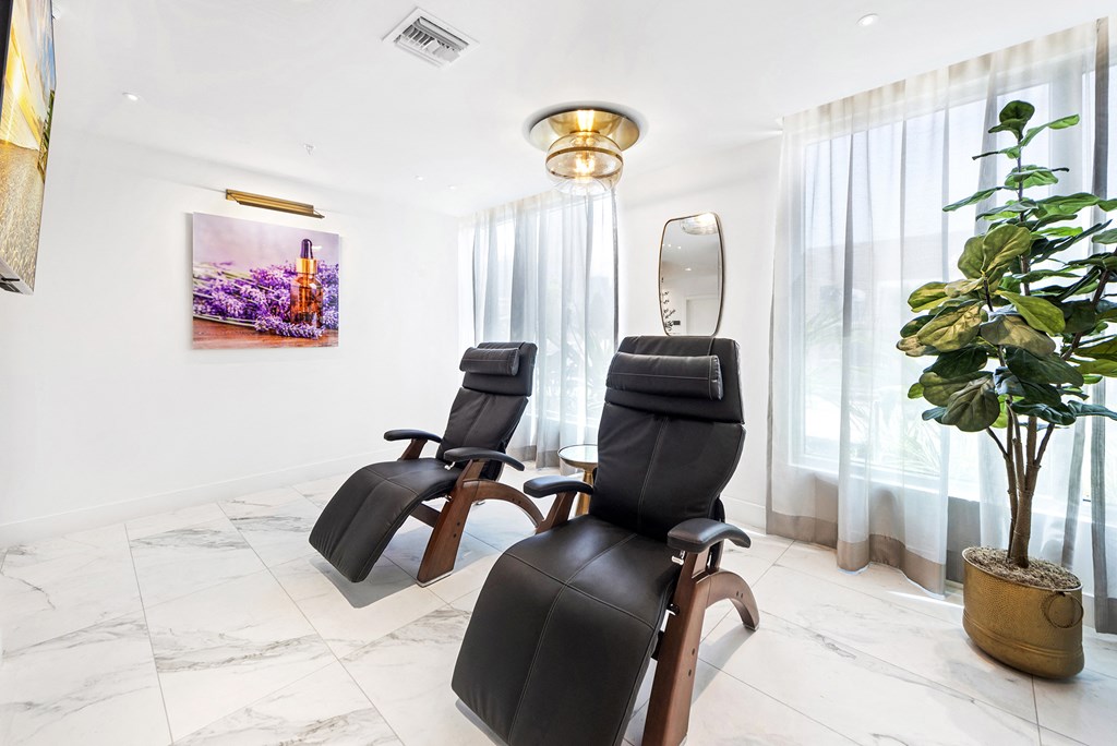 a spa room with three black massage chairs and a potted plant