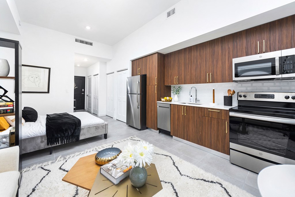 a bedroom with a medium sized bed and a kitchen with stainless steel appliances