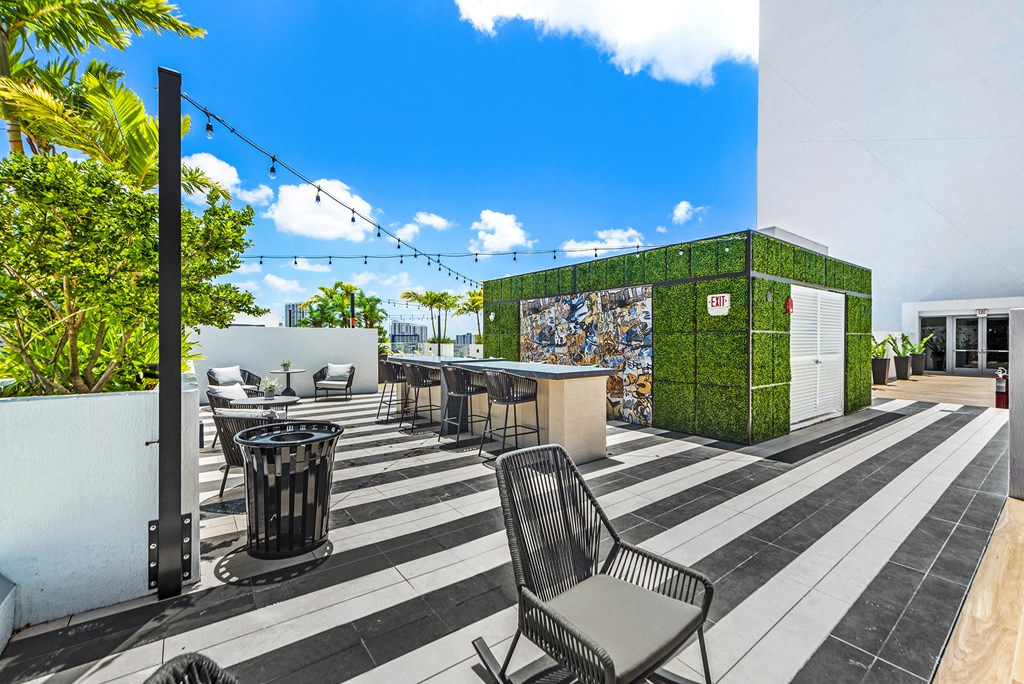 a patio with chairs and tables and a green wall with mosaics on it