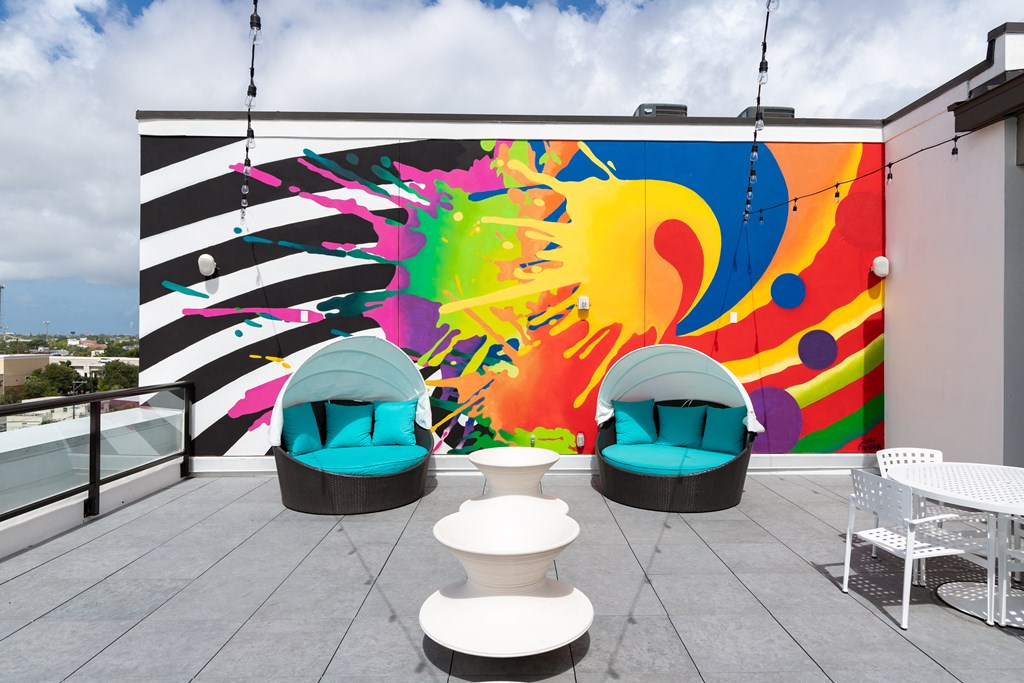 a mural on the side of a building with blue chairs