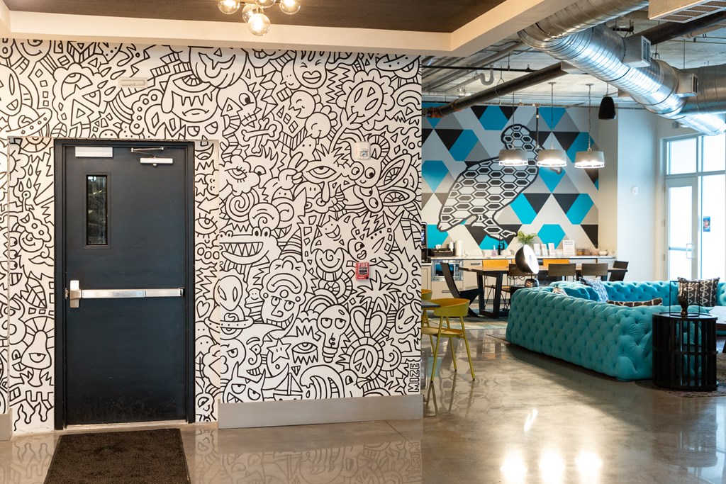 a lobby with a wall mural and a black door