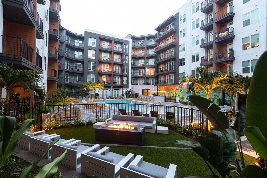 an outdoor living area with a fire pit in front of an apartment building