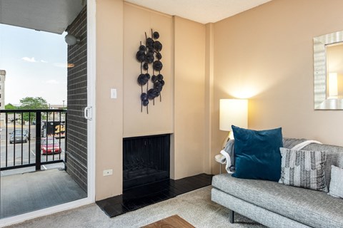 A living room with a grey couch and a fireplace.